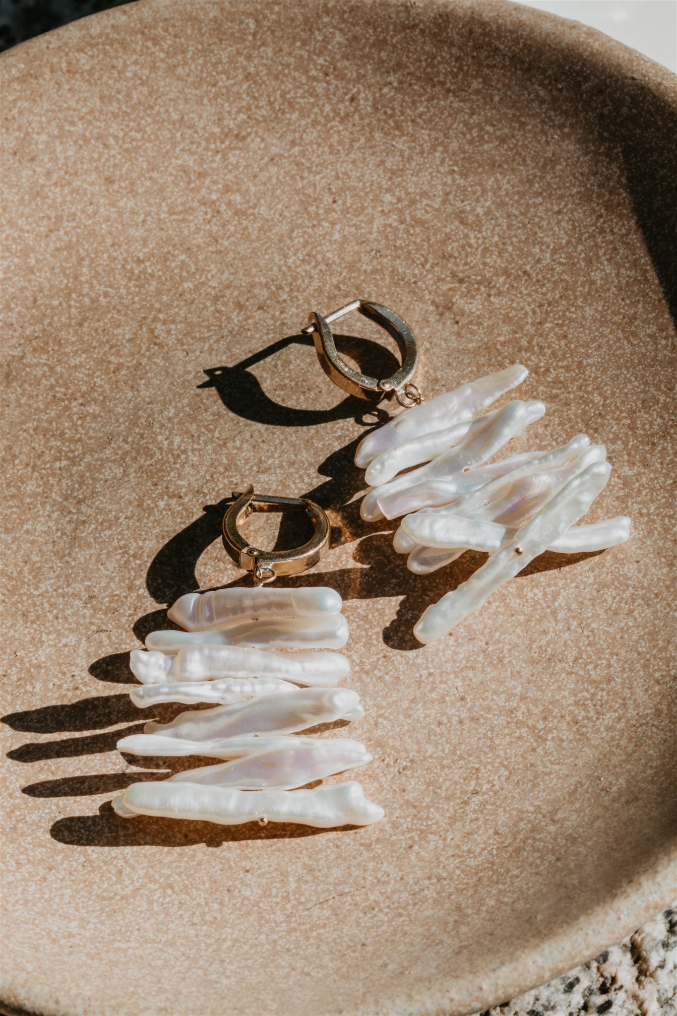 Pair of earrings with pearls on a beige surface