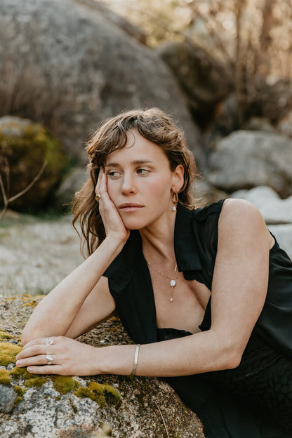Woman in a black dress sitting on rocks with a natural background