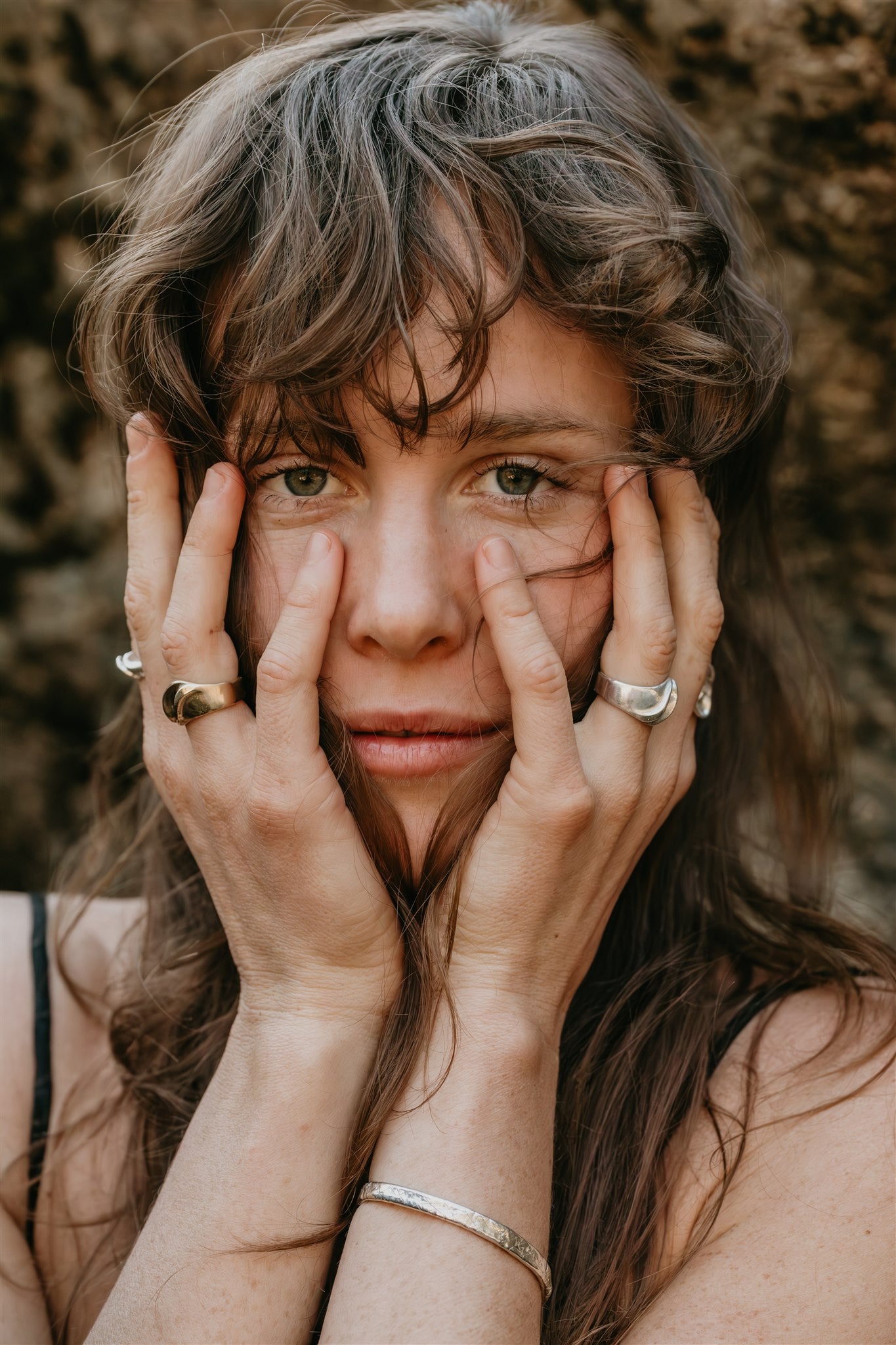 Woman with hands on face against a textured brown background