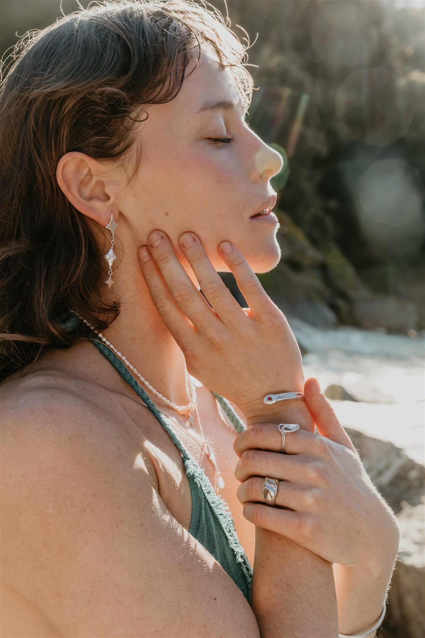 Woman with jewelry outdoors, close-up of face and hands
