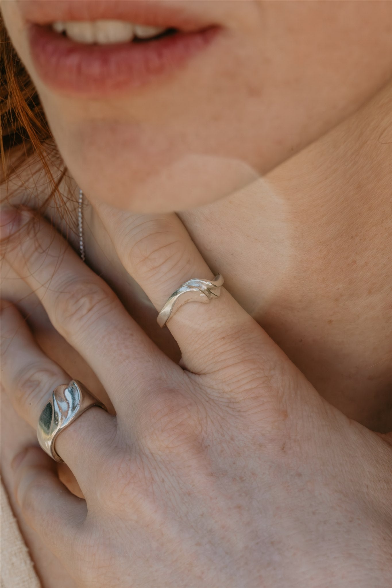 Close-up of a person's hand wearing two silver rings with a blurred background