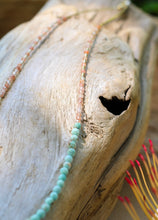 Load image into Gallery viewer, Close-up of a turquoise beaded necklace on a piece of driftwood with blurred background
