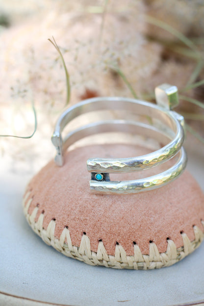 Silver bracelet with a turquoise stone on a pink woven surface