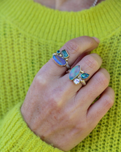 Load image into Gallery viewer, Hand wearing multiple rings with gemstones against a bright green sweater.
