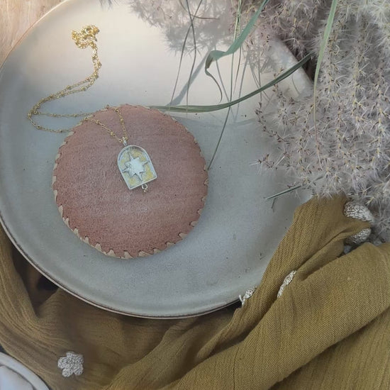 video of arch-shaped pendant with a star detail and a small diamond hanging below